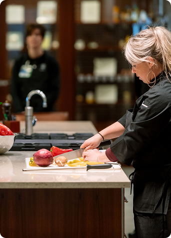 Wellness chef preparing ingredients and demonstrating cooking techniques in a modern kitchen during a group class.